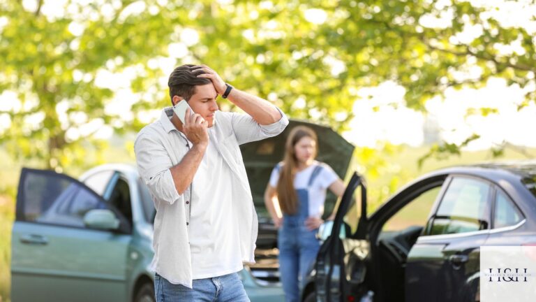 Driver on the phone after a car crash in Georgia, with two damaged cars and the other driver behind him